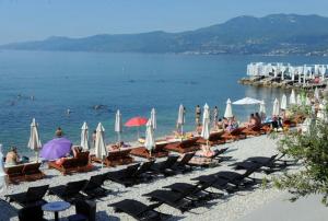 a beach with chairs and umbrellas and the water at Retreat in Rijeka