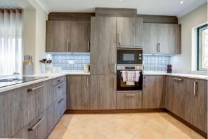 a large kitchen with wooden cabinets and a microwave at 2bedroom bungalow on Gramacho Golf Resort heated shared pool in Carvoeiro