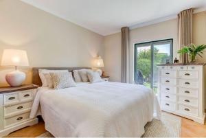 Un dormitorio blanco con una cama grande y una ventana en 2bedroom bungalow on Gramacho Golf Resort heated shared pool en Carvoeiro