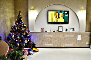 a christmas tree in a lobby with a television at Hotel Astoria in Volgograd