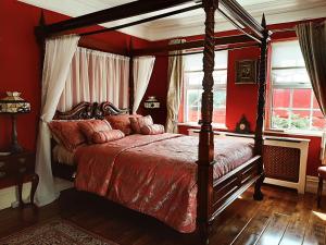 ein Schlafzimmer mit einem Himmelbett mit roten Wänden in der Unterkunft Riverside Lodge in Carlingford