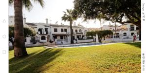 een rij witte huizen met palmbomen in een park bij Bungalow con vistas a la piscina in Torrevieja