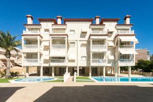 un gran edificio blanco con una piscina frente a él en Fantástico apartamento con piscina, en Santa Pola