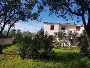 a white house in a field with trees at House Mia in Cala Liberotto