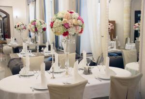 een kamer met witte tafels met witte stoelen en bloemen bij Pansionat Rodina in Essentoeki