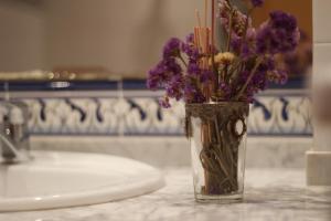 un vaso pieno di fiori viola seduto su un bancone di Casa Rural Apartamento Hernán Cortés a Herrera del Duque