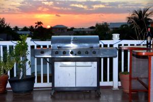 einen Grill auf einem Balkon mit Blick auf den Sonnenuntergang im Hintergrund in der Unterkunft Belizean Nirvana in Placencia Village