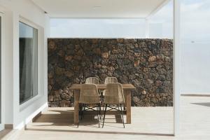 une table avec des chaises et un mur en pierre dans l'établissement ALAVA SUITES, à Costa Teguise