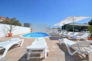 a group of white lounge chairs and a swimming pool at Villa Allegro in Sukošan