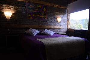 a bedroom with a bed and a brick wall at Wau Purul in Cholila