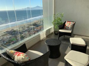 a room with chairs and tables and a view of the ocean at Departamento Club Oceano in Coquimbo