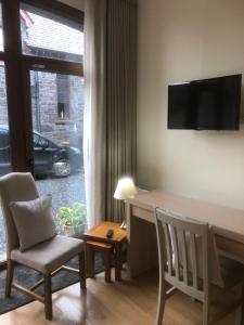 a living room with a desk and chairs and a television at Courtyard Mews in Armagh