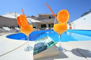 3 verres de jus d'orange à côté de la piscine dans l'établissement Villa Allegro, à Sukošan