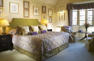 a bedroom with a large bed and a chair at Buckland Manor - A Relais & Chateaux Hotel in Broadway