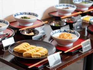 a buffet with bowls of food on a table at Kurayoshi City Hotel in Kurayoshi