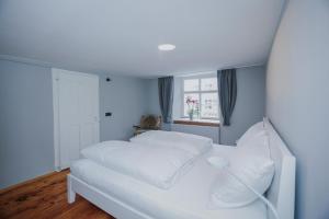 ein weißes Bett in einem Zimmer mit Fenster in der Unterkunft Clara Erdgeschosswohnung im Jüdischen Viertel in Hohenems
