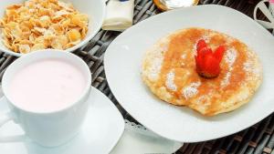 a plate of pancakes with a strawberry on it and a cup of coffee at Hospederia Villa de los Sáenz in Villa de Leyva