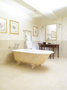a large bath tub in a bathroom with a desk at Buckland Manor - A Relais & Chateaux Hotel in Broadway