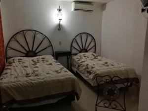 two beds sitting next to each other in a room at Hotel Posada del Angel in Mérida