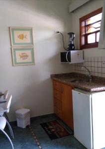 a small kitchen with a counter and a microwave at Apto no IlhaFlat em frente Mar in Ilhabela