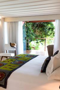 a bedroom with a large white bed with a window at Insólito Boutique Hotel & Spa in Búzios