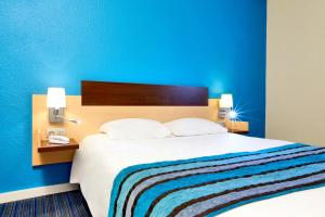 - une chambre avec un grand lit et un mur bleu dans l'établissement Kyriad Viry-Chatillon, à Viry-Châtillon