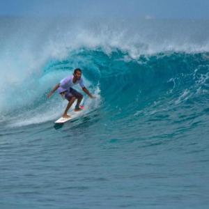 un hombre montando una ola en una tabla de surf en el océano en String Wave Maldives, en Gulhi