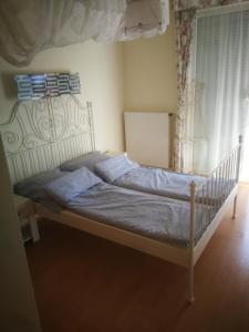 - une chambre dotée d'un lit avec un cadre blanc dans l'établissement Promenade Apartman, à Balatonlelle