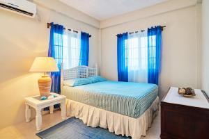 CanouanAtlantic Breeze Apartments, Canouan Island的一间卧室配有一张带蓝色窗帘和灯的床