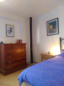 een slaapkamer met een bed en een dressoir met een blauwe deken bij Casa Libertad in Órgiva