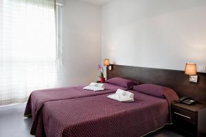 a bedroom with two beds with towels on them at Residhotel Les Hauts d'Andilly in Andilly