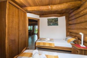 two beds in a room with wooden walls at Baranjska eko drvena kuća in Kopačevo