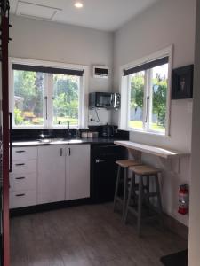 - une cuisine avec des placards blancs, un comptoir et 2 fenêtres dans l'établissement Birch Hill Cottage -30 minutes from St Arnaud, à Wairau Valley