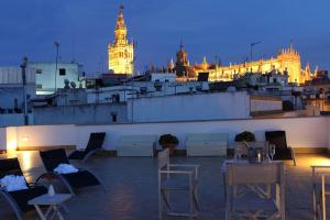 eine Dachterrasse mit Stühlen und ein Gebäude mit einem Uhrturm in der Unterkunft Petit Palace Marques Santa Ana in Sevilla