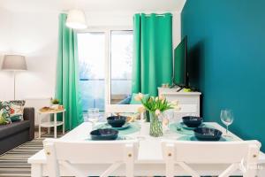 a living room with a white table and green curtains at Feniks Apartamenty - Vacation Park SPA in Kołobrzeg