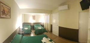 Habitación con 2 camas verdes y sofá en Hotel Pachá Anexo en Salta