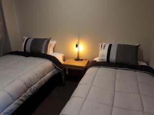 two beds in a room with a lamp on a table at South City Accommodation unit 3 in Invercargill