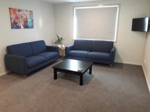 ein Wohnzimmer mit 2 blauen Sofas und einem Couchtisch in der Unterkunft South City Accommodation unit 3 in Invercargill