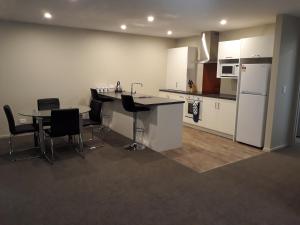 South City Accommodation unit 3 في إنفيركارجِِيل: مطبخ مع طاولة وكراسي وثلاجة