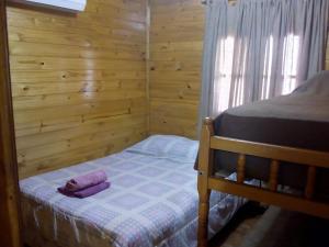 a small bedroom with a bed and a wooden wall at O NEGRAÕ in Puerto Iguazú