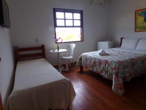 um quarto com 2 camas, uma mesa e uma janela em Kazaya Pousada em Araruama
