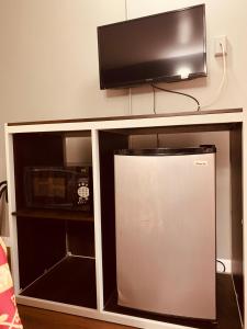 einen TV über einem Entertainment-Center mit einem Kühlschrank in der Unterkunft Red Carpet Inn - Norristown in Norristown