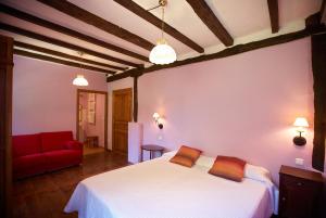a bedroom with a white bed and a red couch at Casa Rural Goikola in Deba