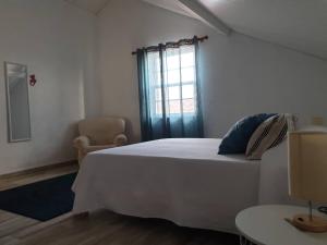 a bedroom with a white bed and a window at Quinta do Calvário in Lajes das Flores