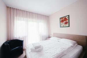 um quarto com uma cama branca e uma cadeira preta em Hotel - Pension Vesta em Bad Elster