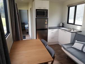 eine kleine Küche mit einem Tisch und einem Kühlschrank in der Unterkunft Opunake Beach Kiwi Holiday Park in Opunake