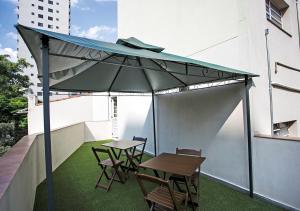 een patio met een tafel en stoelen en een parasol bij Hospedaria Lumo Domo Praça da Árvore in Sao Paulo