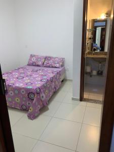 a bed in a room with a purple comforter at Apê de Mainha in Ilhéus