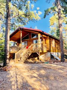 a log cabin in the woods with a porch and stairs at Adventure Awaits 3King Bed,2Bath Log Cabin in heart of Duck Creek Village! in Duck Creek Village