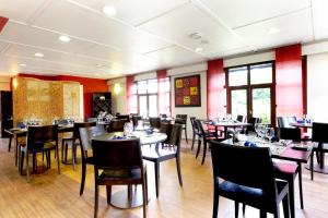 a dining room with tables and chairs and windows at Kyriad Angers Sud Ponts-De-Cé in Les Ponts-de-Cé